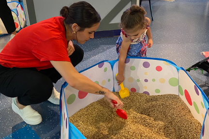 child life specialist scooping sand with young girl