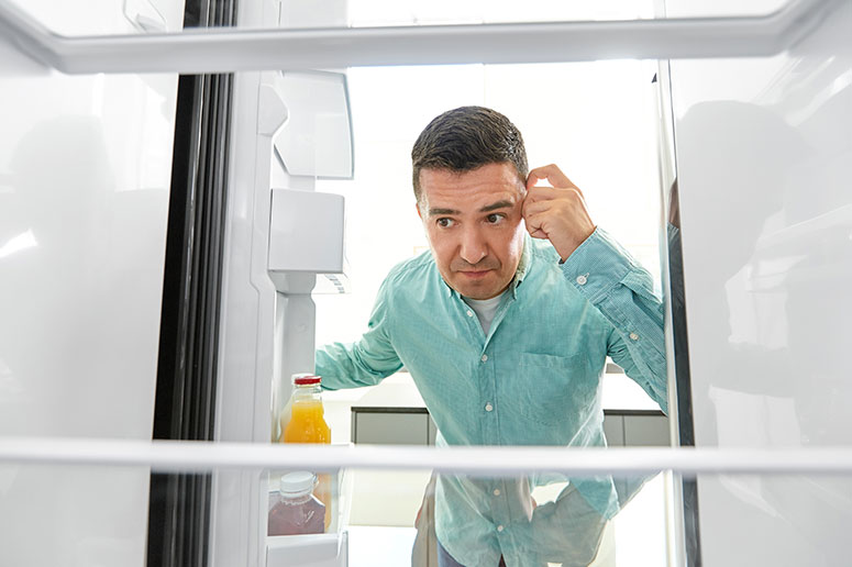 Man looking in fridge thinking about what to eat