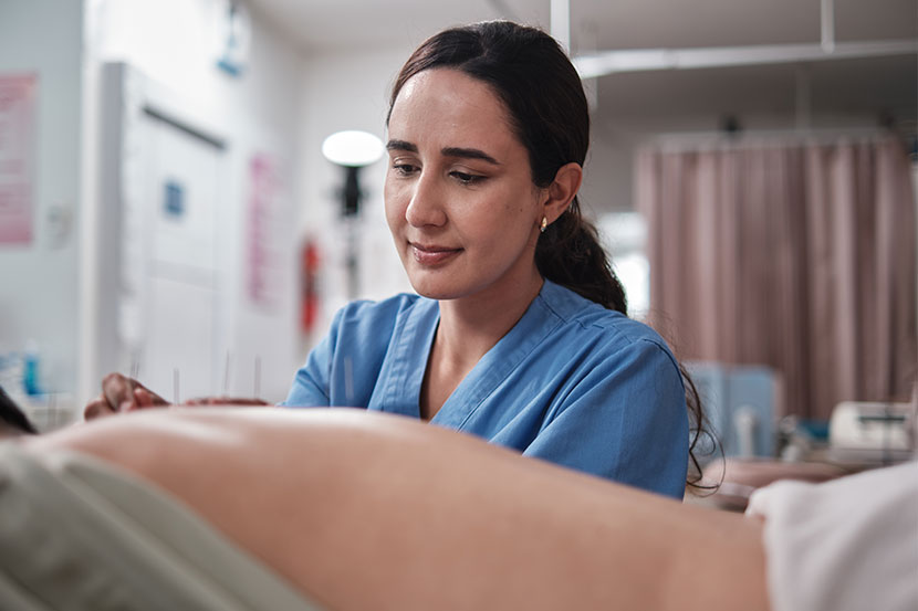 Healthcare worker doing acupuncture on a patient.