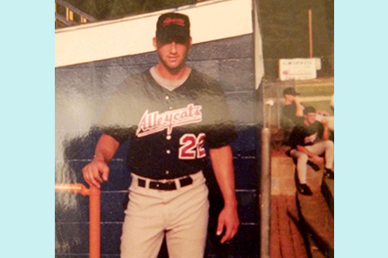 An old photo of Scott posing proudly in his 'Alleycats' baseball team uniform.